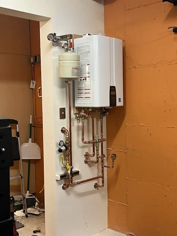 Plumbing technician inspecting water heater connections in Sheridan